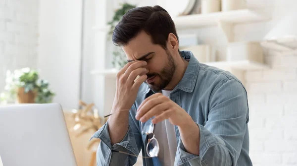 Hombre enfermo cansado tomando de gafas, masajeando puente nasal — Foto de Stock