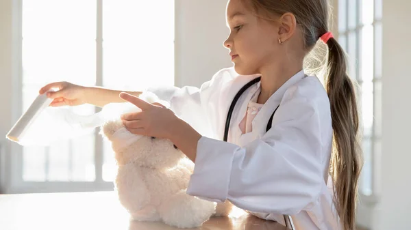 Schattige kleine kleuter verband hoofd van teddybeer. — Stockfoto