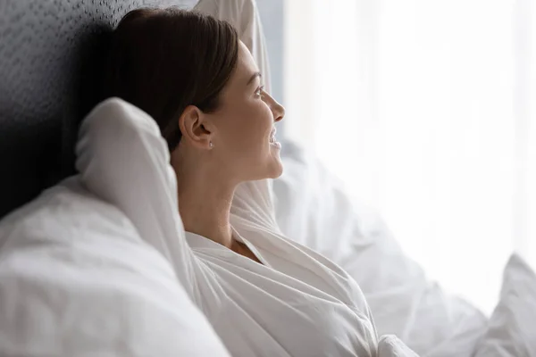 Посміхаючись приваблива молода брюнетка, жінка насолоджується хорошим ранковим часом у ліжку . — стокове фото