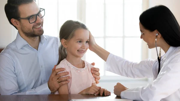 Freundlicher Hausarzt streichelt Kopf einer kleinen entzückenden Patientin — Stockfoto