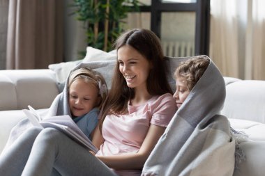 Sevgi dolu anne küçük çocuklara kitap okuyor.