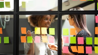 Çeşitli çalışanlar yapışkan kağıtlarla ilgili notları tartışıyor, proje planlıyorlar