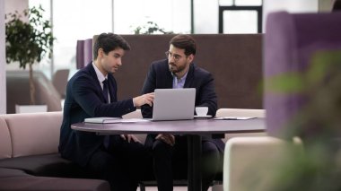 Odaklanmış erkek meslektaşlar dizüstü bilgisayarla yapılan iş projesini tartıştılar