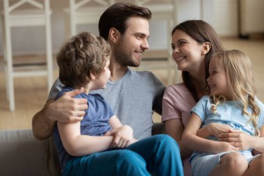 Mutlu ebeveynler kucaklaşır. Küçük çocuklarla rahatlar.