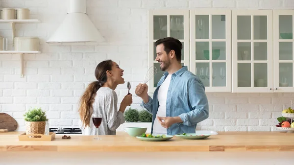 Glückliches Liebespaar beim Singen, Spaß mit Geschirr in der Küche — Stockfoto