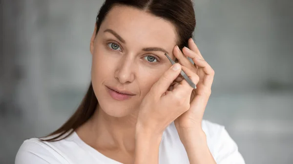 Young pretty lady doing eyebrows correction procedure. — Stock Photo, Image