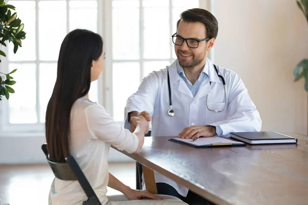 Angenehmer Arzt begrüßt junge Frau bei Vorsorgeuntersuchung in Privatklinik. — Stockfoto