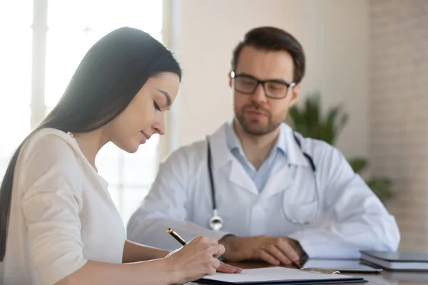 Focus on concentrated young female patient reading medical insurance agreement. — Stock Photo, Image