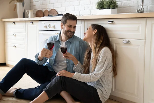 Happy young wife and husband drinking wine, sitting on floor — Stock Photo, Image