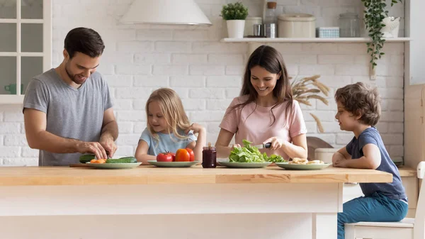 Glad ung familj med barn matlagning hemma kök — Stockfoto