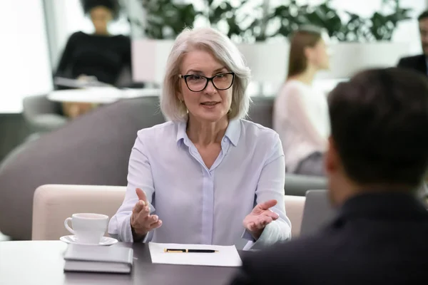 Medelålders affärskvinna pratar med arbetssökande vid intervjun — Stockfoto