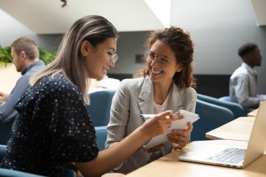 Mutlu çeşitli meslektaşlar, birlikte proje üzerinde çalışırken eğleniyorlar.