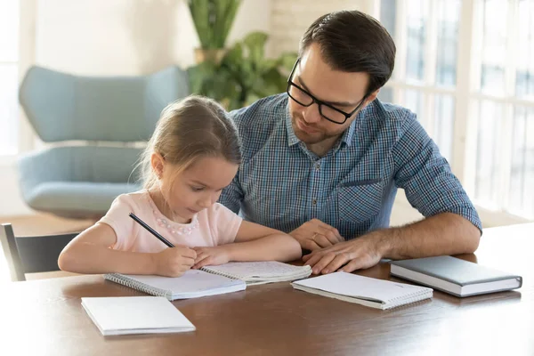 Caring young father helping little daughter with homework. — Stock Photo, Image