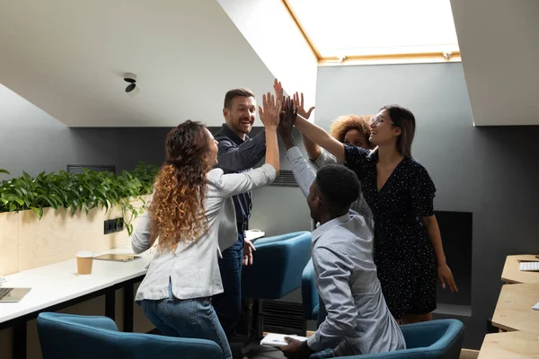 Happy diverse employees team giving high five at briefing