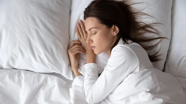 Wanita muda tenang menikmati istirahat malam yang baik di tempat tidur yang nyaman . — Stok Foto