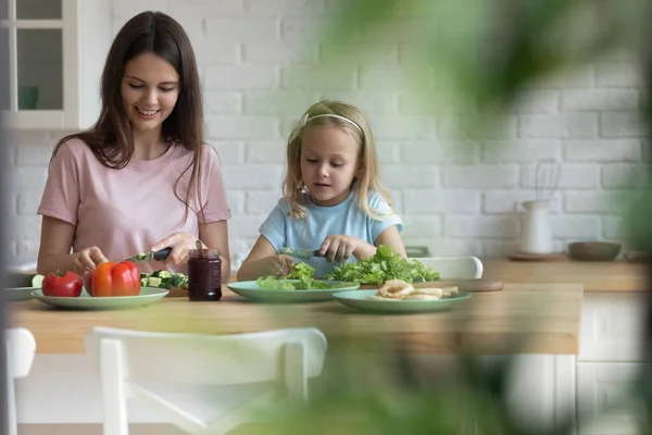 Ung mamma och liten dotter gör sallad hemma — Stockfoto