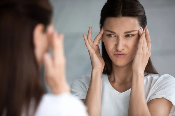 Ongelukkig jong brunette vrouw ontevreden met eerste rimpels. — Stockfoto