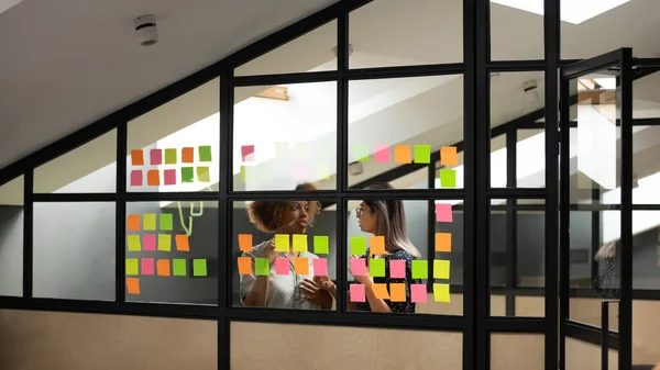 Olika kollegor diskuterar projektplan för klibbiga papper på kontoret — Stockfoto