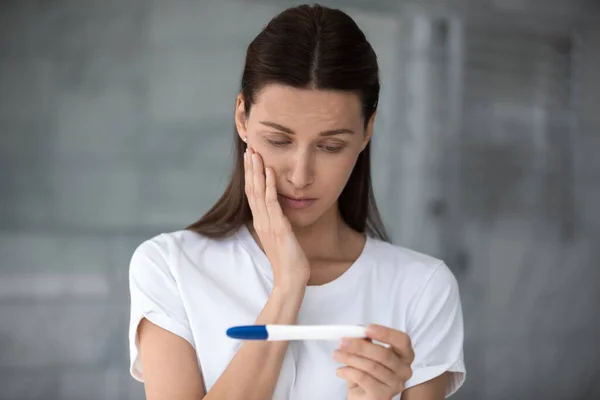Unhappy frustrated young woman looking at plastic test. — Stock Photo, Image