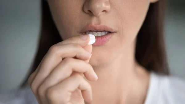 Unhealthy young woman taking round pill, suffering from ache. — Stock Photo, Image