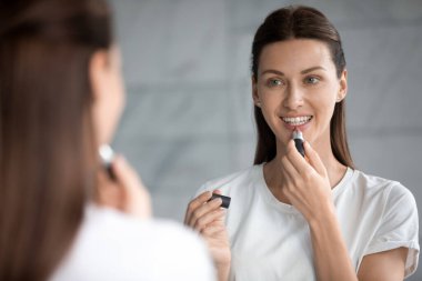 Çekici genç bir kadın dudaklarına en sevdiği ruju sürüyor..