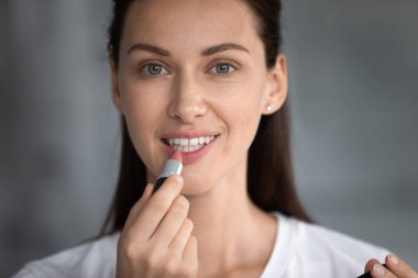 Genç bir kadın dudaklarına gülsüz ruj sürüyor..