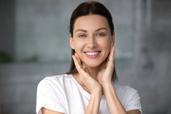 Donna sorridente che tocca le guance, soddisfatta di una buona condizione della pelle . — Foto Stock