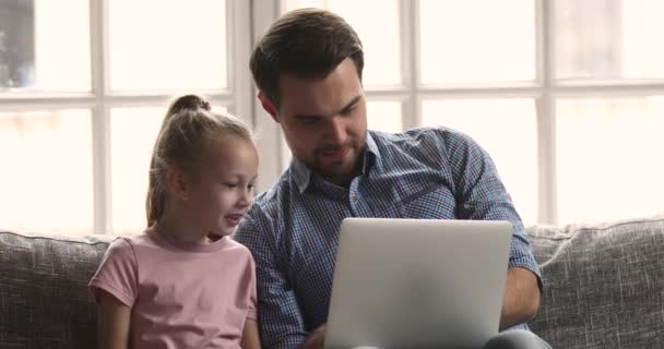 Sorrindo pai mostrando vídeos engraçados no laptop para a filha pequena . — Vídeo de Stock