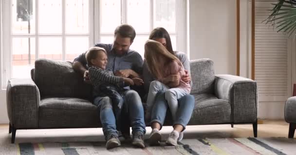 Glückliches junges Ehepaar kitzelt kleine süße Kinder. — Stockvideo