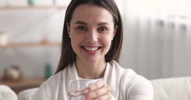 Smiling healthy woman holding glass of water looking at camera — Stock Video