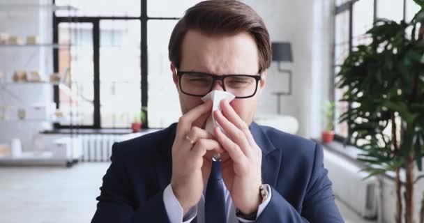 Hombre de negocios alérgico enfermo que tiene síntomas de alergia que sopla la nariz corriente — Vídeo de stock