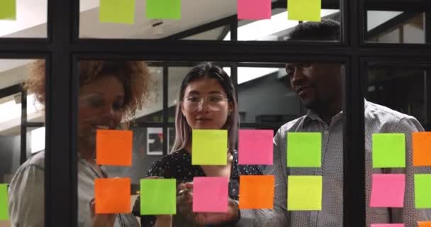 Fröhliche gemischte Rasse junge Kollegen arbeiten in der Nähe von Kanban Board zusammen. — Stockvideo