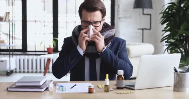 Kontorsarbetare som sitter på arbetsplatsen med medicinblåsande näsa — Stockvideo