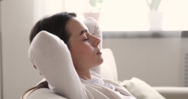 Mujer joven y serena relajándose en el sofá respirando aire, de cerca — Vídeos de Stock