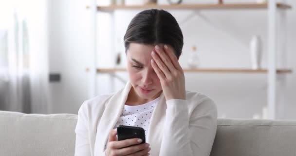Mujer joven preocupada leyendo malas noticias en el mensaje en el teléfono inteligente — Vídeos de Stock