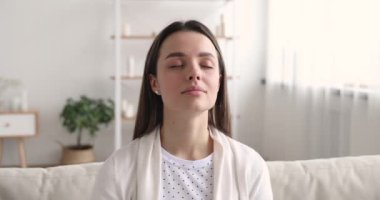 Sakin genç kadın evde gözleri kapalı meditasyon yapıyor.