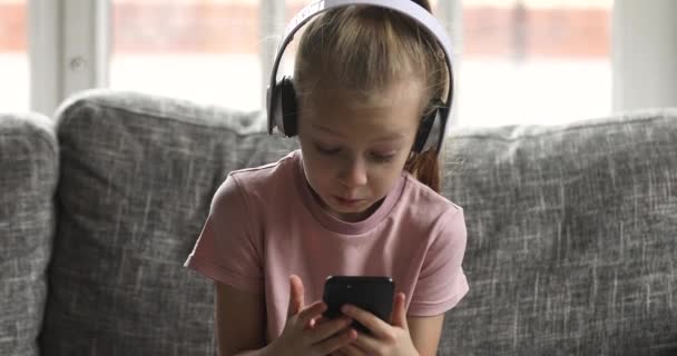 Bonito menina criança pequena ouvir música, jogando jogo móvel . — Vídeo de Stock