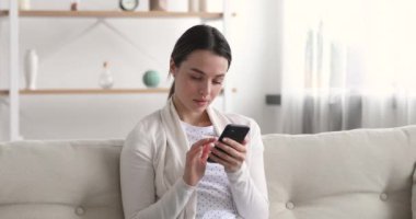 Kazanan teklifi kutlayan neşeli genç bir kadın akıllı telefona bakıyor.