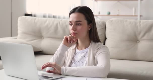 Серйозна зосереджена жінка за допомогою комп'ютерного мислення тримає руку на підборідді — стокове відео