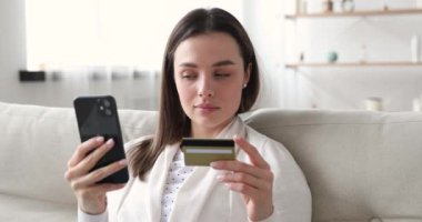 Gülümseyen kadın tüketici kredi kartıyla online akıllı telefondan alışveriş yapıyor.