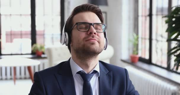 Feliz tranquilo hombre de negocios profesional escuchando música en la oficina, primer plano — Vídeo de stock
