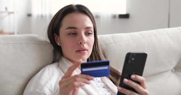 Glad ung kvinna som innehar kreditkort med hjälp av mobila betalningar — Stockvideo