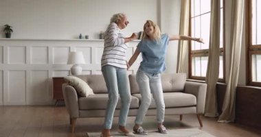 Heyecanlı yaşlı olgun kadın evde yetişkin kızıyla dans ediyor..