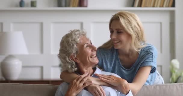 Glimlachende jong liefdevolle vrouw omarmen van terug ouder volwassen mama. — Stockvideo