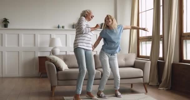 Excited elderly mature woman dancing with grownup daughter at home. — Stock Video