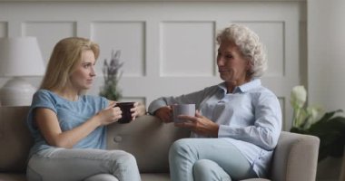 Kanepede oturan mutlu genç bayan, yaşlı annesiyle sohbet ediyor..