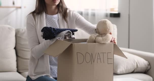Γυναίκα συσκευασίας ρούχα και αρκουδάκι σε κουτί δωρεά παιδιών — Αρχείο Βίντεο