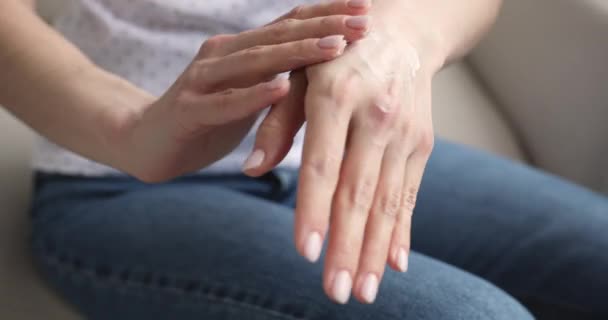 Young woman applying moisturizing cream on hands, close up view — Stock Video