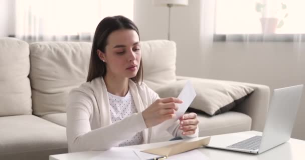 Opgewonden jonge vrouw leest goed nieuws in brief thuis — Stockvideo