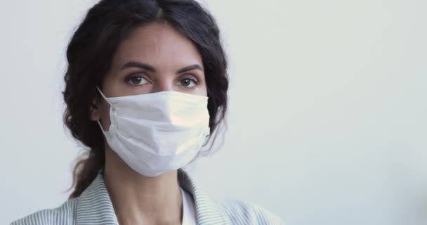 Молодая женщина с вирусной инфекцией смотрит в камеру в маске — стоковое видео